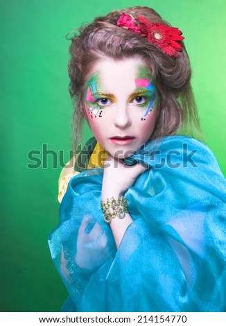 Spring fairy. Young woman in creative image posing with bright fabric's and flowers.