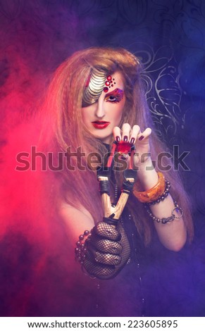 Halloween.Young woman in artistic image with one-eyed visage posing with smoke