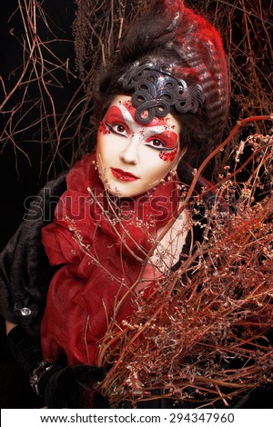 Young plump woman in creative image  in russian style  with artistic red and white visage  and with twigs