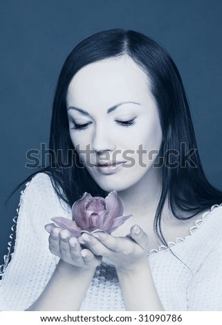 Portrait of young woman with orchid in cold tones