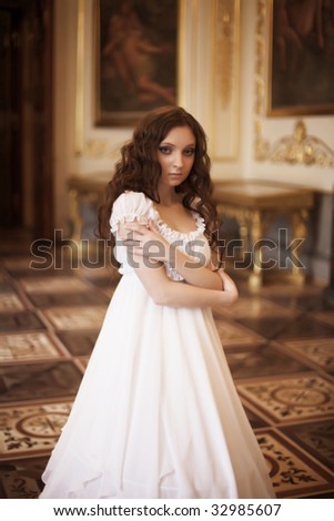 Young beautiful woman standing in the palace room.