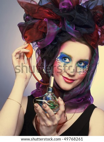 Young woman in hat with bows with vintage bottle of perfume in her hands