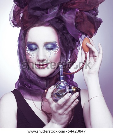 Young woman in hat with bows with vintage bottle of perfume in her hands