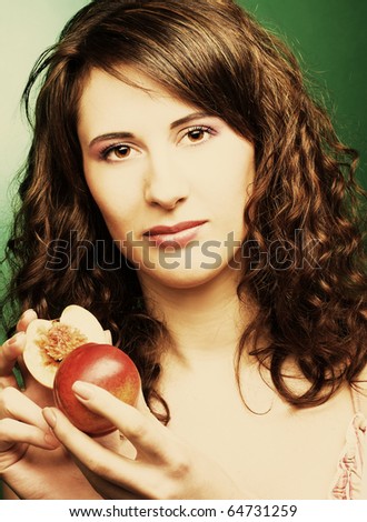 Young woman on the bright green background with peaches in her hands