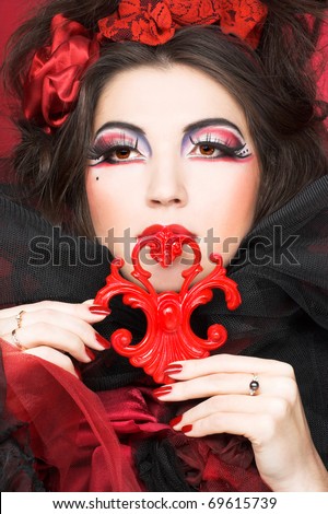 Queen of hearts. Creative lady in black and red colors and with bright make-up.