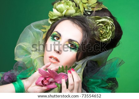 Young lady with artistic visage and with flowers in her hands and hair