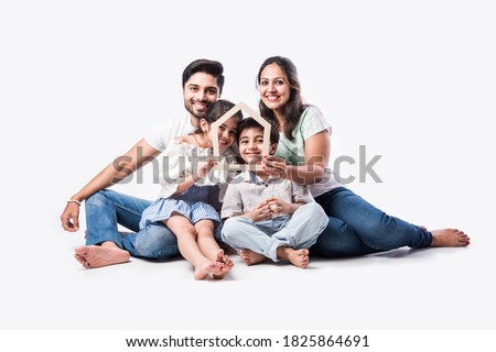 Indian family Father, mother, son and daughter holding 3D paper model of home - Real Istate Concept in India