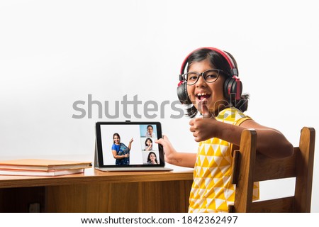 Cute Little Indian girl studying online using her laptop or Tablet computer at home or attending school during corona pandemic or lockdown