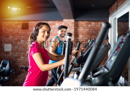 Indian asian attractive couple doing cardio training program in fitness center or gym, selective focys - health and fitness concept
