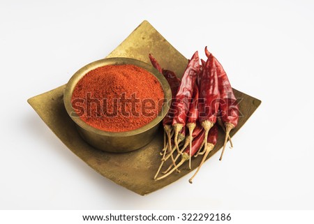 closeup of red dry chilli powder with red dry chillies in a square brass bowl and brass plate,front view, isolated on white background, indian spices