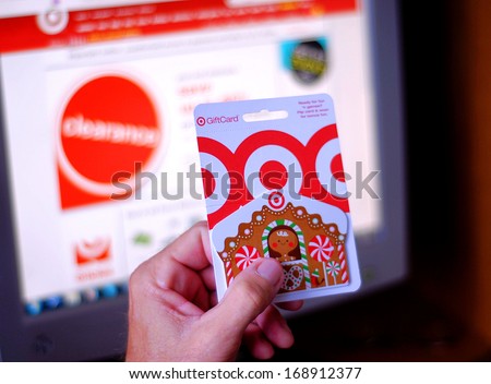 WEST PALM BEACH, FL - DECEMBER 28, 2013: A  man\'s hand is holding a Target gift card, getting ready to use it for on line purchases during after Christmas shopping at a clearance sale.