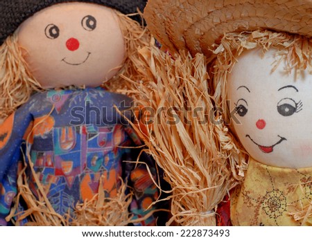 close up detail of country scarecrow couple. The female doll is the focal point of the image with her male counterpart slight out of focus. They are a rustic looking couple with straw accents.