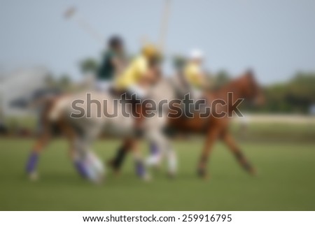 Background blur of equestrian polo players competing. The horses are visibly in action. The polo field is green grass. Horses are brown and white. Sense of speed and power is concept.