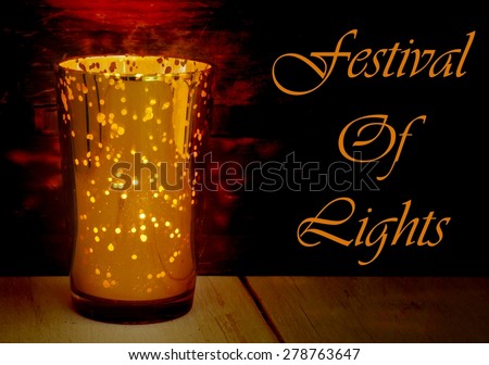 Low key image of a golden glass candle holder with many points where light can come through. Rustic wood textures below and behind the candle pick up the warm tones. Message of festival of lights