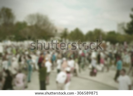 Background blur of crowd at political rally in the United States holding signs and carrying US flags for upcoming election cycle in 2016 presidential campaigns. Copy space. Vintage filter added.