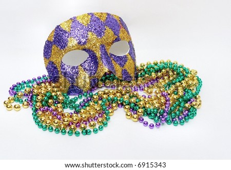 Horizontal image of green, gold and purple mardis gras beads and a purple and gold harlequin mask covered with glitter to commemorate the February celebration that is a huge holiday in New Orleans.