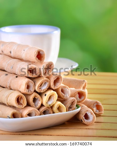 tasty creamy wafer rolls on the table with tea cup