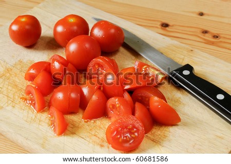 a few of tomatoes on a wooden plate side by side. some tomatoes cutted