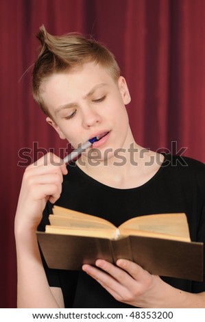 The teenager in a black vest reads the book