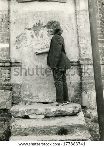VORONEZH, USSR - CIRCA 1986: An antique photo shows portrait of girl drawing a cat on the wall of an old building