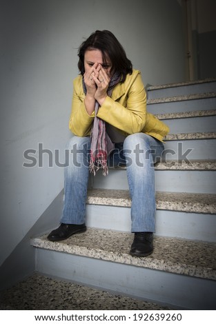 Sad woman sitting on the stairs in the entrance of a house