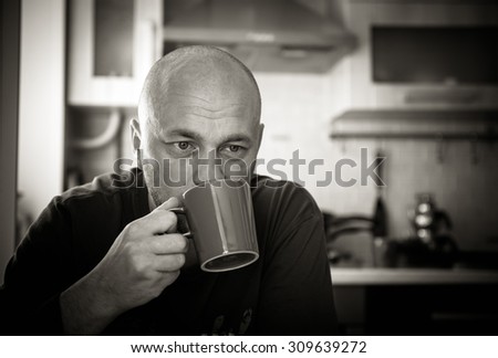 Bald man drinking tea. Black and white photo