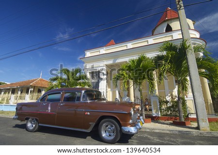 CIENFUEGOS, CUBA - FEBRUARY 1: car on February 1, 2007 in Cienfuegos: view of a typical Cuban car parked on the street, with decades old, these vehicles are still used. A woman rests on the porch.