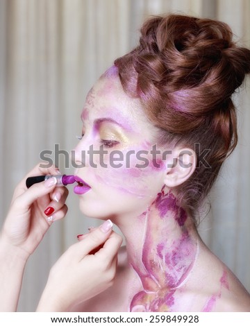 Makeup artist applies lipstick. Beautiful woman face. Perfect makeup
