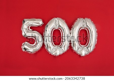 From above of silver shiny balloons demonstrating number 500 on red background with scattered glitter 商業照片 © 