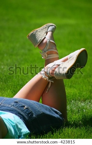 Lace-up summer sandals on young lady laying in a field