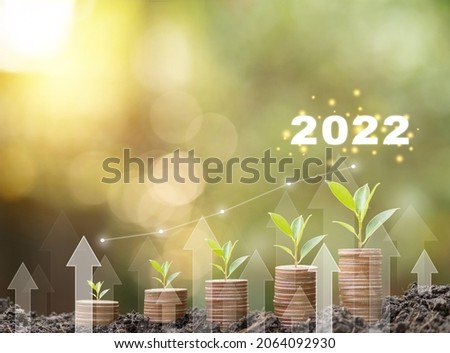 2022 new year Save money, success goals and investment growth concept. Stack coins on ground with white arrows rising on green nature background. Financial and business, Management money retire, tax. 商業照片 © 