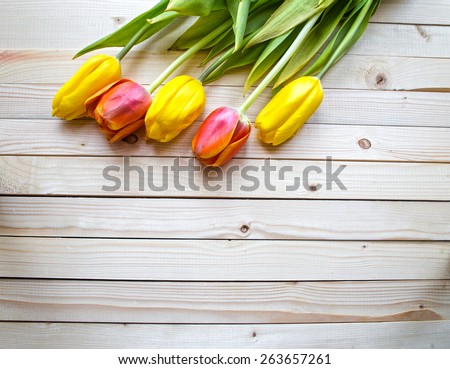 Yellow and orange tulips on a wooden table, top viev gorisontal shot