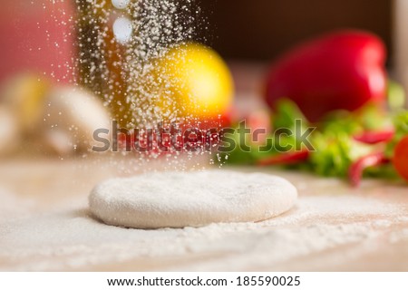 Dough for Italian pizza preparation. Falling flour.