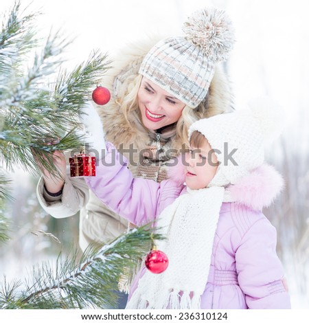 Happy mother and child decorating christmas tree outdoor wintertime