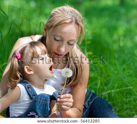Mother and daughter in jeans with dandelion outdoor