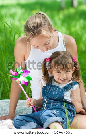 Smiling mother and daughter in jeans with colorful toy outdoor