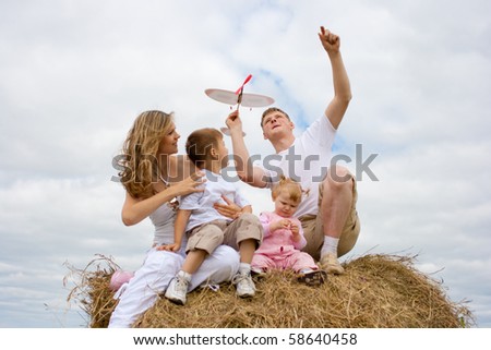 Happy family launching toy aircraft model sitting on haystack together