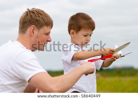 Father and son have fun with toy aircraft model in park