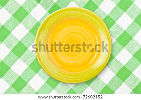 Round yellow plate on green checked tablecloth