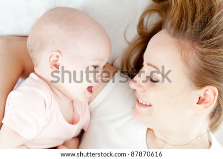 Happy young mother and her baby in bed top view