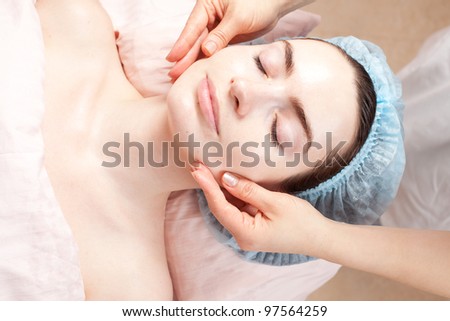 Beautiful woman with clear skin getting beauty treatment - massage of her face at salon