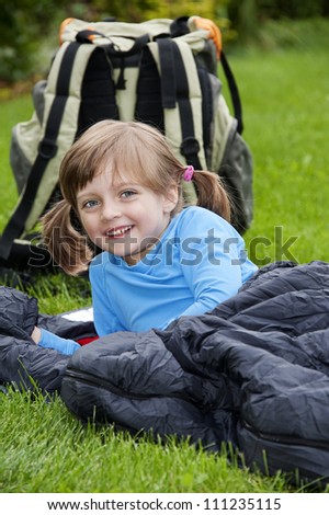 little girl camping laying on a sleeping bag