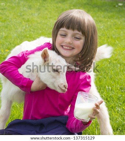 little girl drinking healthy goat milk on a meadow