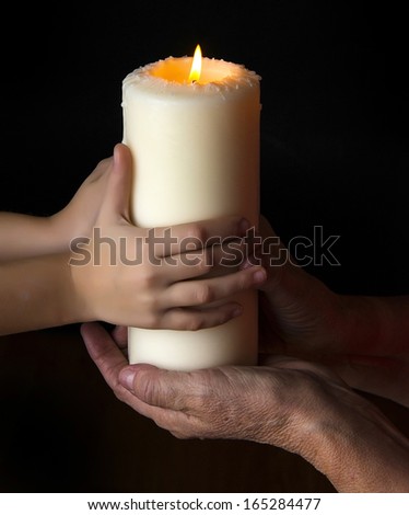 old hands and young hands holding a candle - concept
