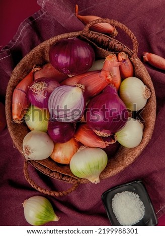 top view of different onions in basket with salt on bordo cloth and red background Stok fotoğraf © 