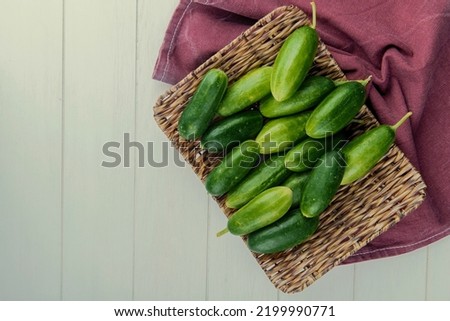 top view of cucumbers in basket plate on bordo cloth on right side and wooden background with copy space Stok fotoğraf © 