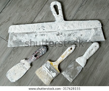 painting tools; spatulas and brushes on the wooden background; plastering tools