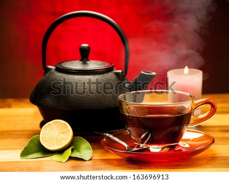 a cup of black tea with teapot in the background