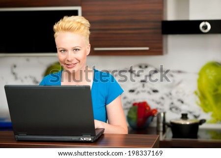 Woman checking mail on laptop in kitchen at home