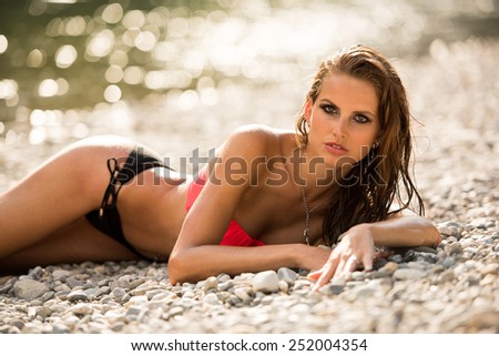 Preety woman in swimsuit near alpine river in early summer afternoon